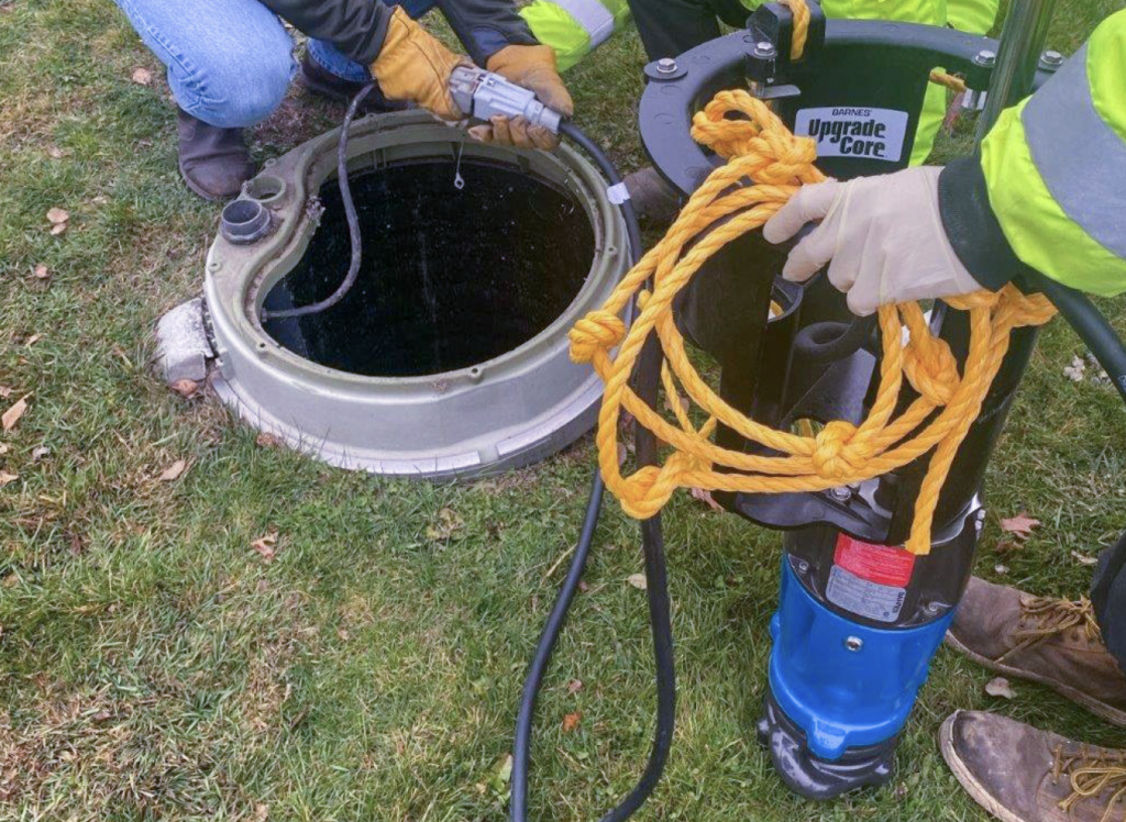 Grinder pump being installed into a whole in the ground.